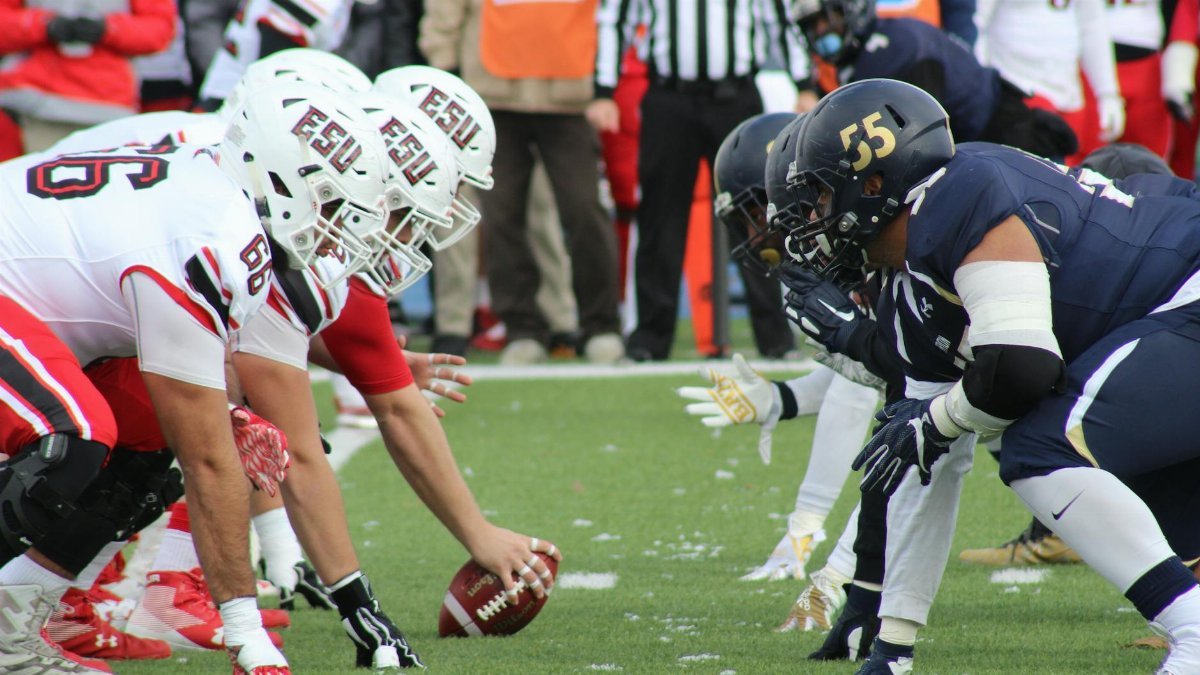 Rival football teams face off at the start of an action-packed game on the field.