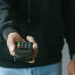 Hand offering a wireless payment terminal for transactions. Modern cashless payment technology.