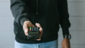 Hand offering a wireless payment terminal for transactions. Modern cashless payment technology.
