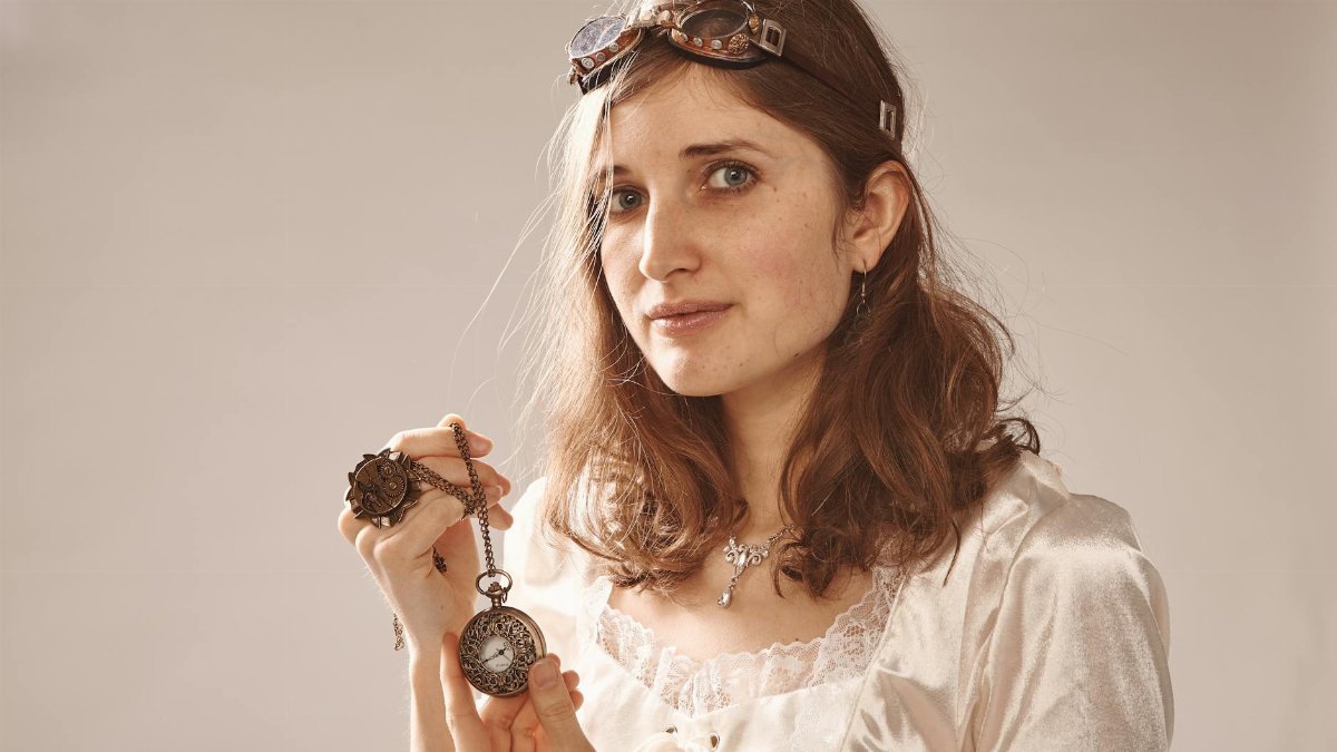 Woman in vintage steampunk attire holding a pocket watch, exhibiting a classic style.
