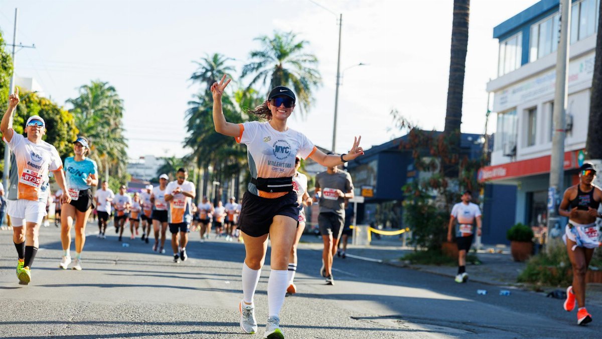 Energetic marathon runners participating in a bustling city street race on a sunny day.