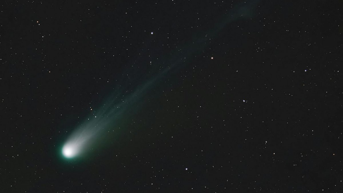A breathtaking view of a bright comet trailing through the night sky amidst numerous stars.
