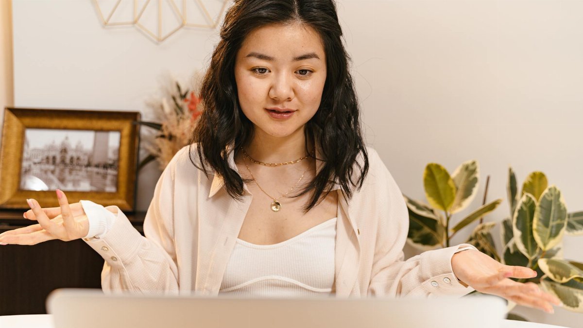 Professional woman gesturing during an online meeting, engaging in a video call from a home office.