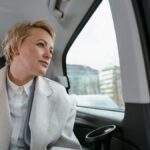 Businesswoman in a car, gazing thoughtfully out the window during a business trip.