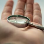 A detailed close-up of a hand holding a magnifying glass, showcasing precision and focus.