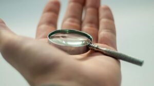 A detailed close-up of a hand holding a magnifying glass, showcasing precision and focus.