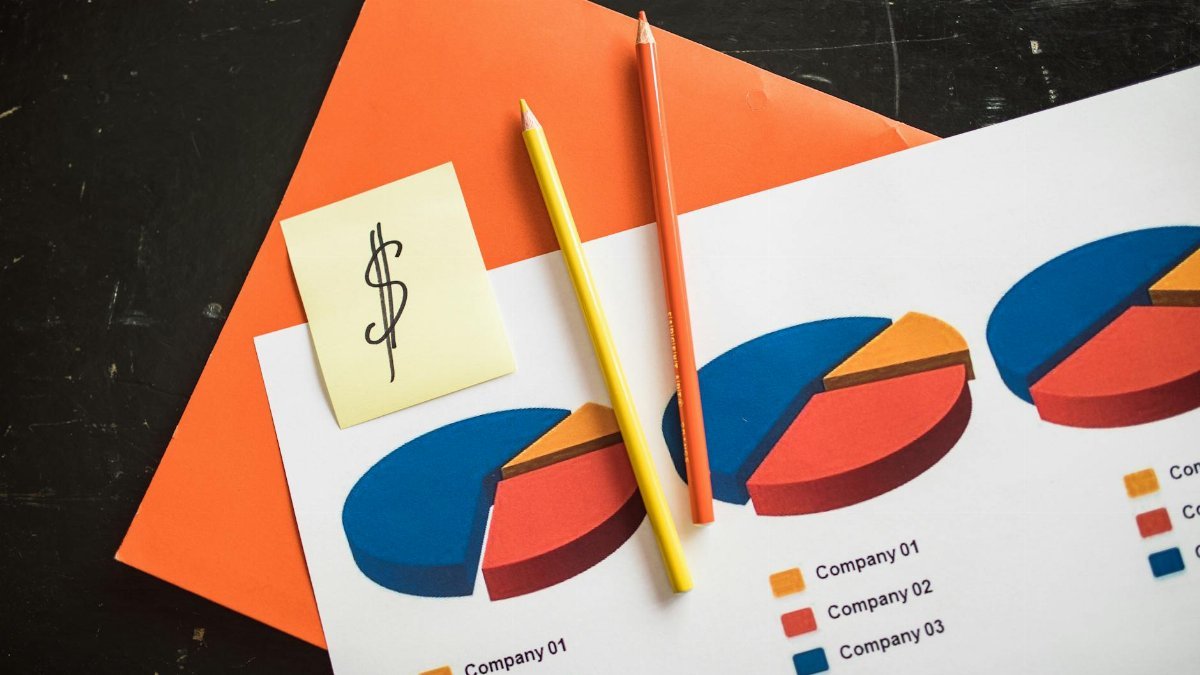 A creative arrangement of financial pie charts with colorful pencils and a dollar note, perfect for business themes.