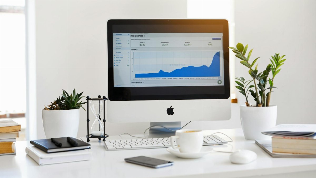A clean, contemporary workspace featuring a desktop with analytics on the screen and plants for a fresh look.