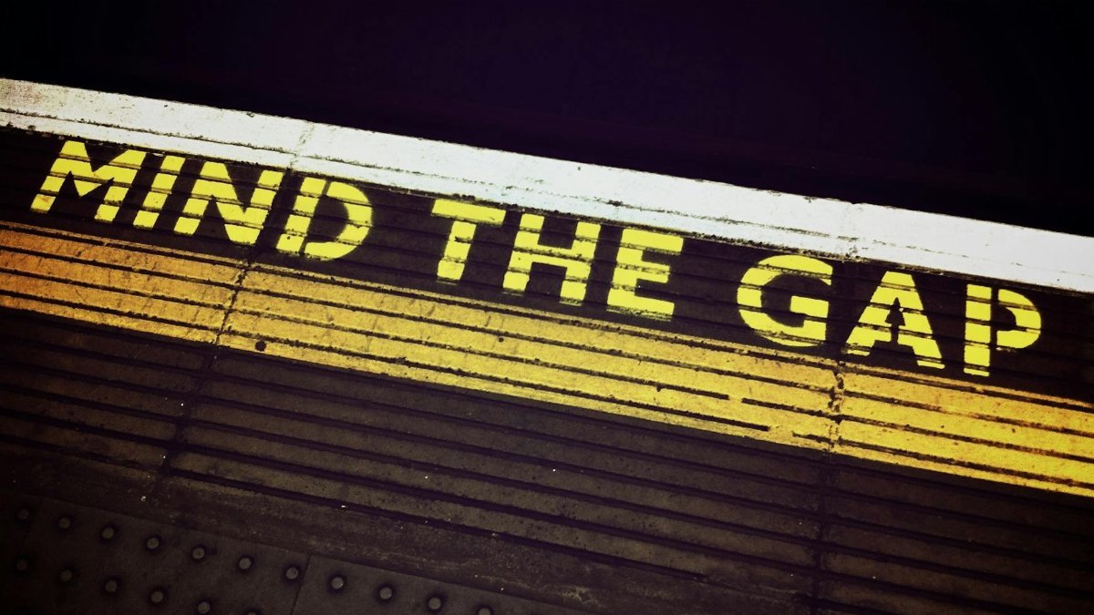 Bold 'Mind the Gap' text on a subway platform, emphasizing passenger safety.