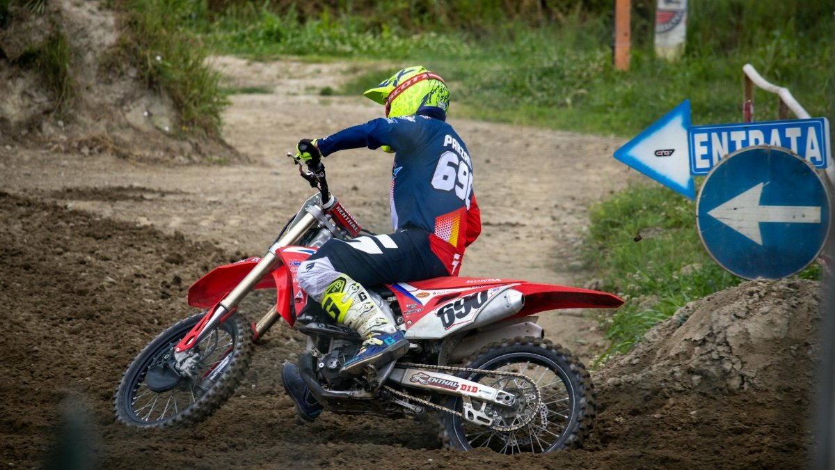 Action shot of a motocross rider turning on a dirt track, showcasing dynamic motion and skill.