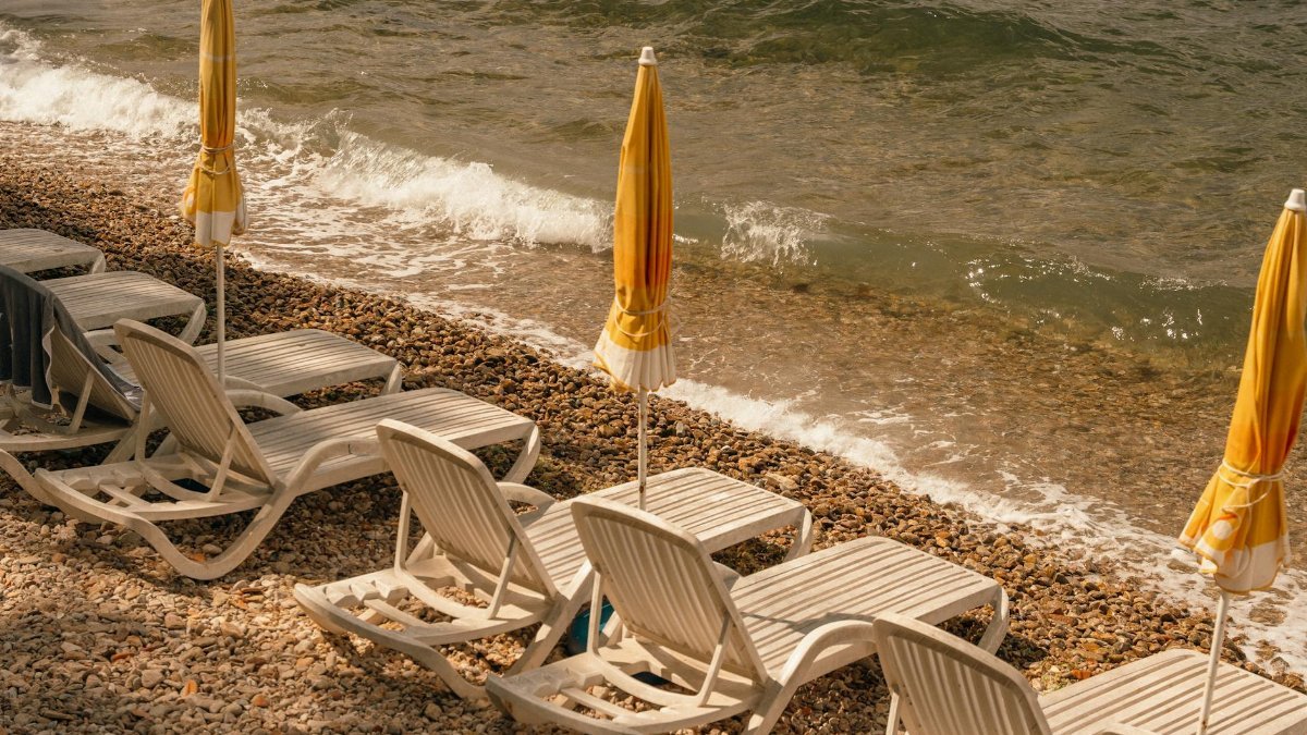 Serene pebble beach with sunbeds and umbrellas, captured during a golden summer sunset.