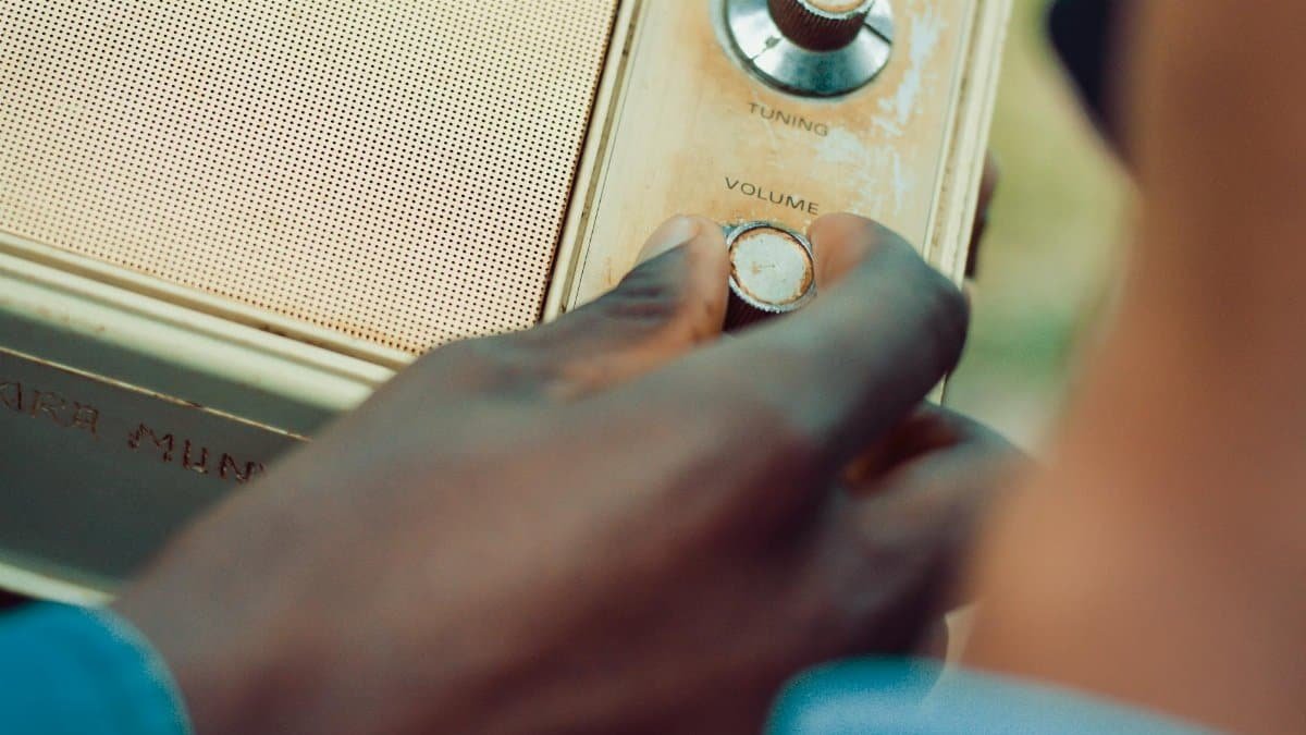 Hand adjusting volume on a vintage radio in an outdoor setting.
