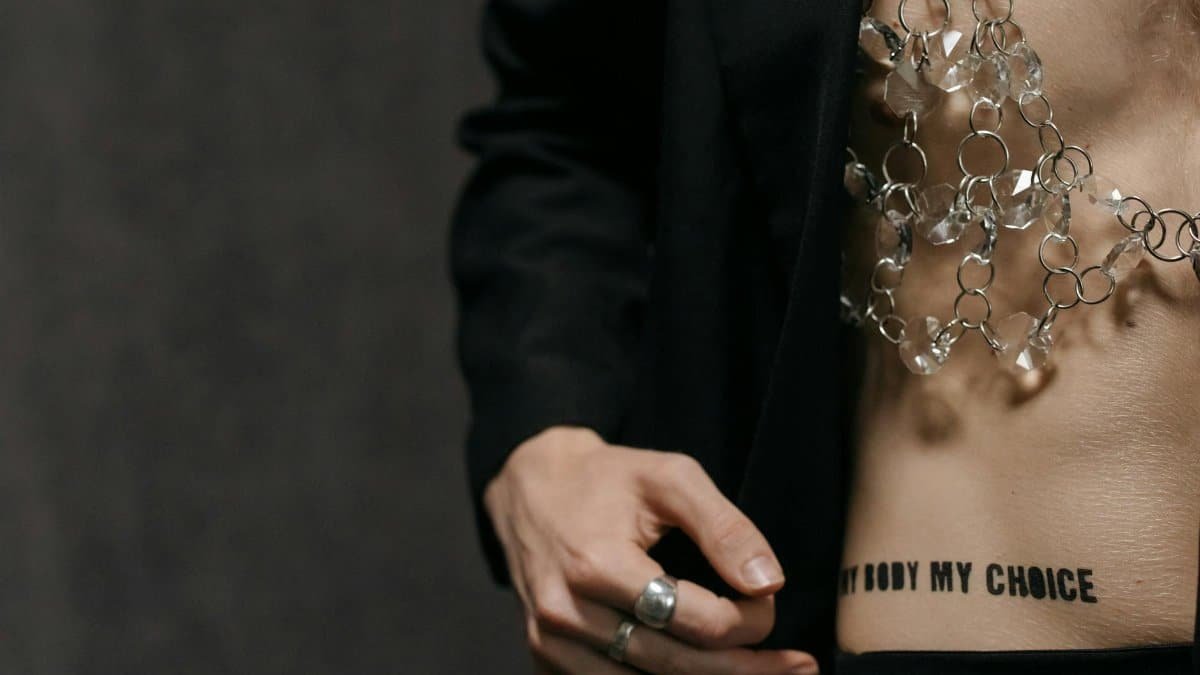 Close-up of a fashion statement with crystal accessory and 'my body my choice' tattoo.