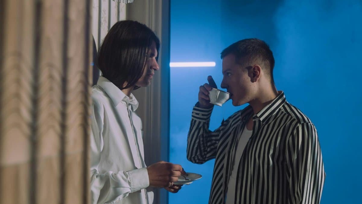 Two men engaging in conversation while enjoying tea in an indoor setting.