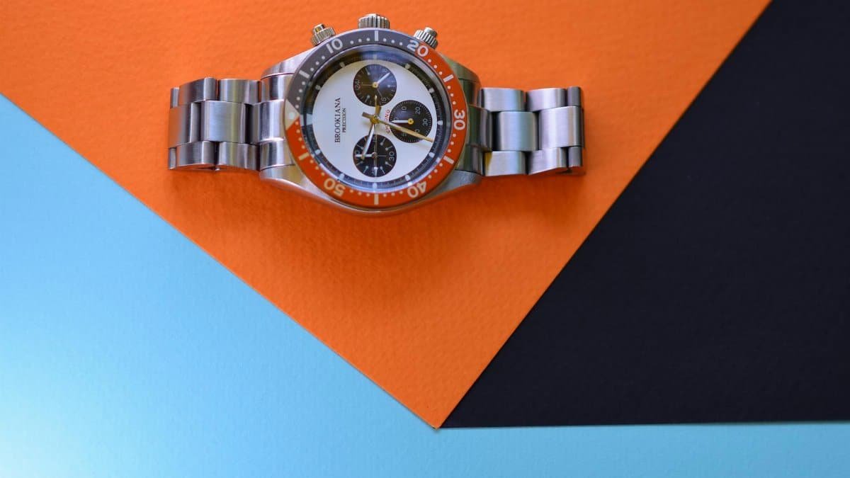 Silver luxury watch displayed on a colorful geometric background highlighting design and elegance.