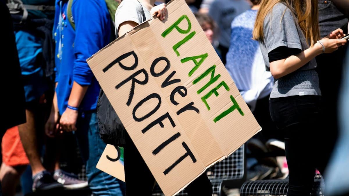 Youth climate protest with participants holding 'Planet Over Profit' sign.
