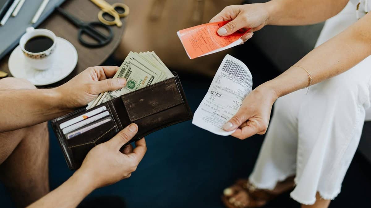 Close-up of a financial transaction involving cash and receipts over a coffee table.