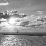 Black and white seascape with dramatic clouds and sunset over the ocean.