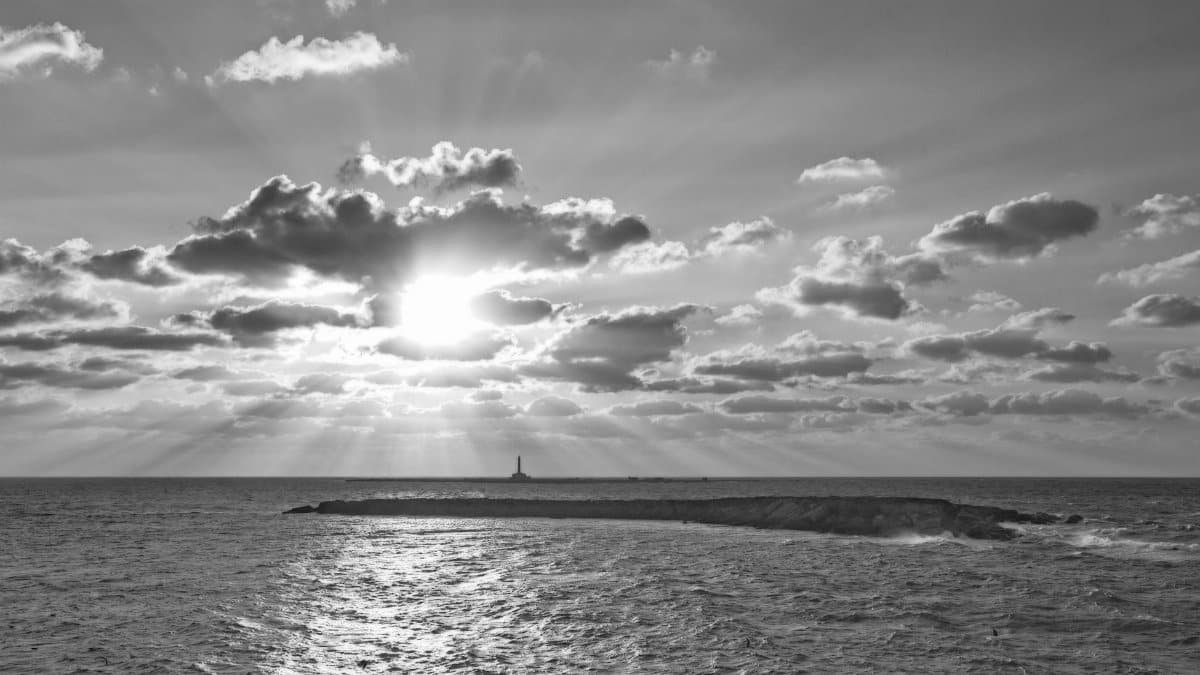 Black and white seascape with dramatic clouds and sunset over the ocean.