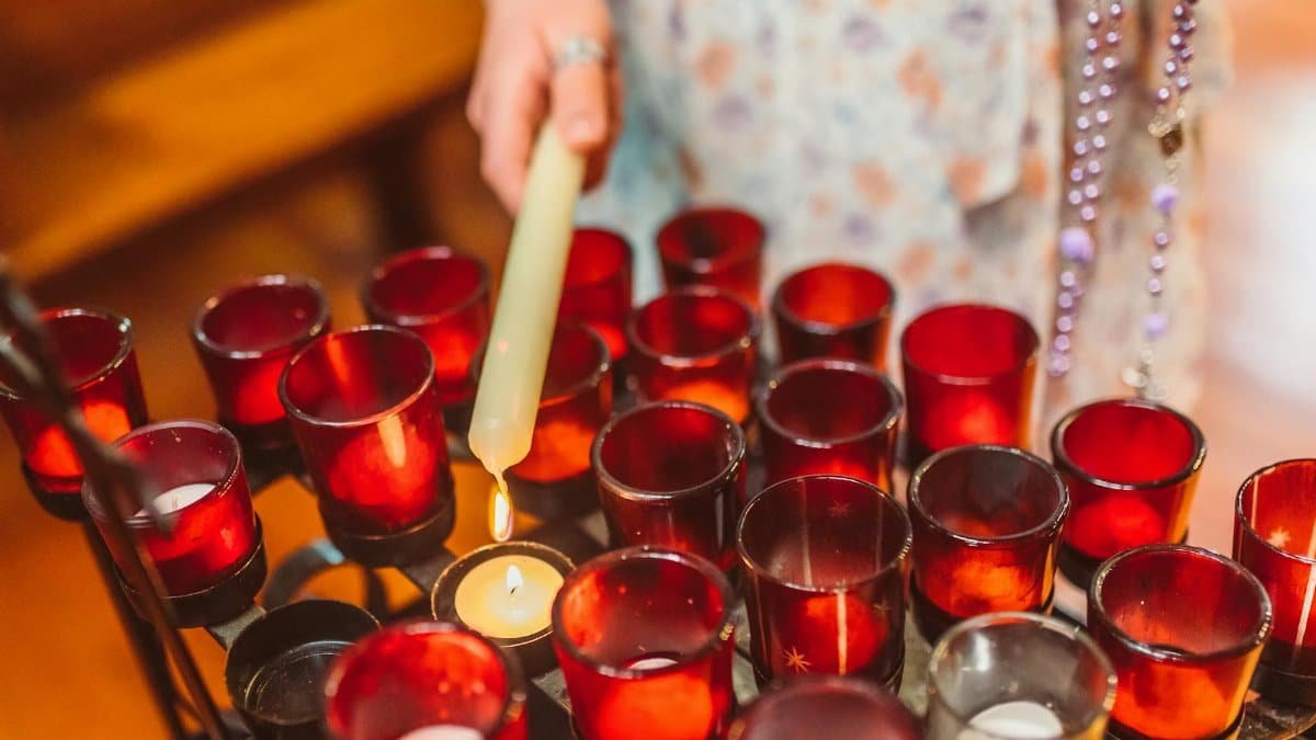 A person lighting votive candles in a church, creating a warm and spiritual atmosphere.