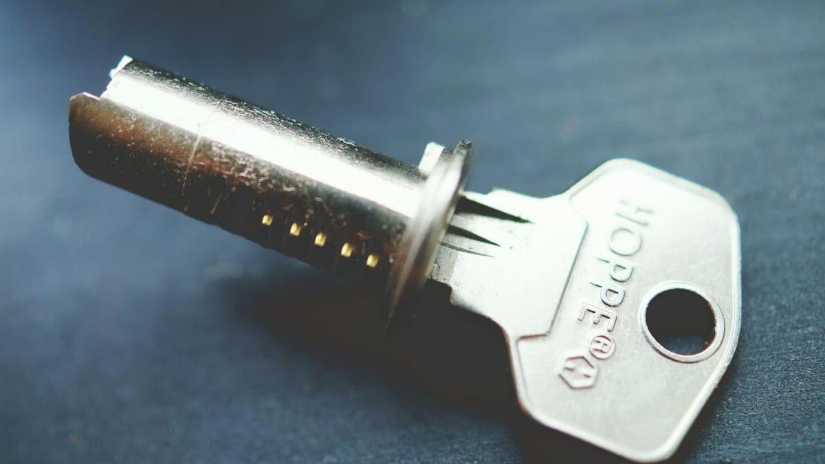 Detailed close-up image of a metallic key with lock cylinder on a dark surface, highlighting intricate details.