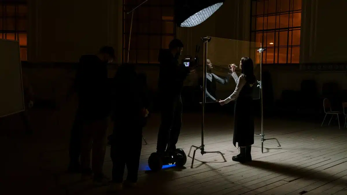 A film crew captures a performer during a dramatic indoor scene with professional lighting.