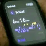 Close-up of a smartwatch displaying sleep tracking data in German.