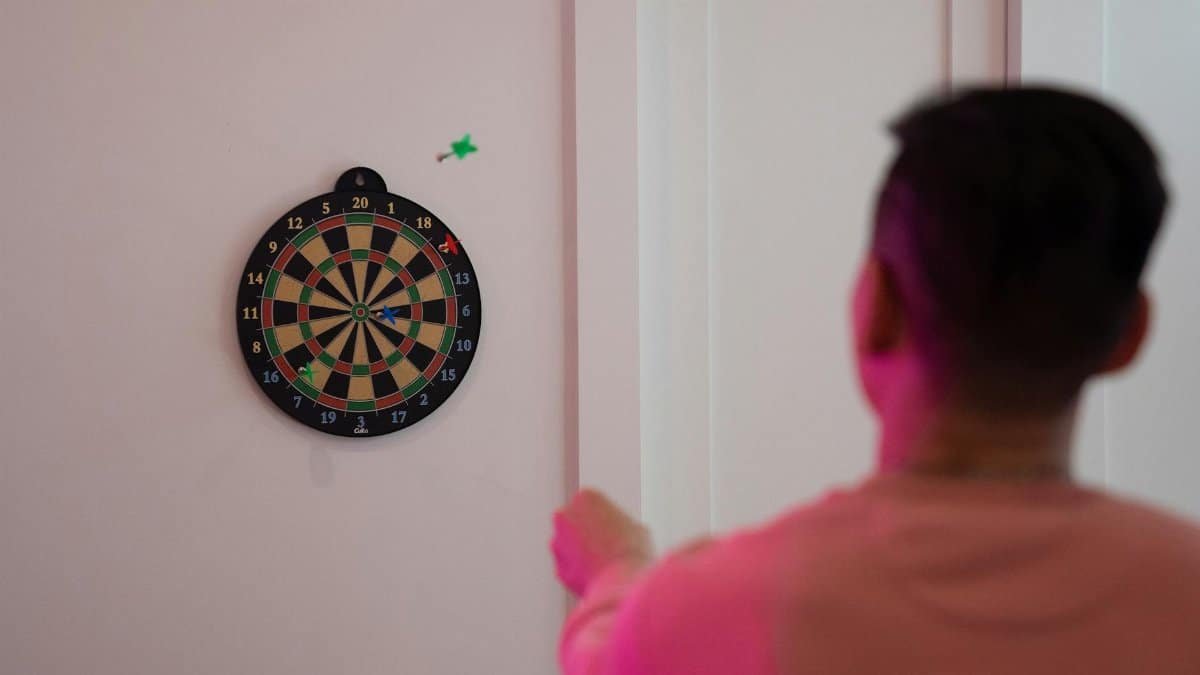 A person aims at a dartboard on a wall, showcasing precision and focus.