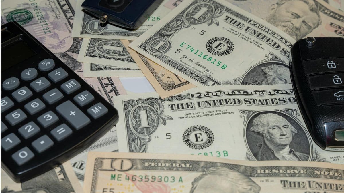 Close-up of various US banknotes, calculator, and car key illustrating finance concept.