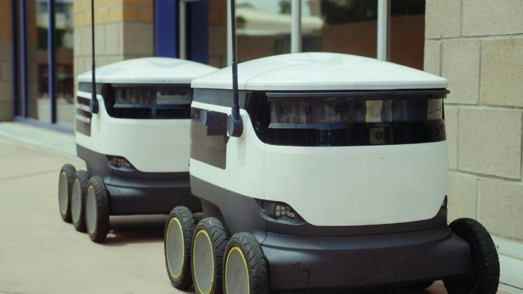 Two autonomous delivery robots positioned outside a modern building, showcasing innovation in robotics and mobility.