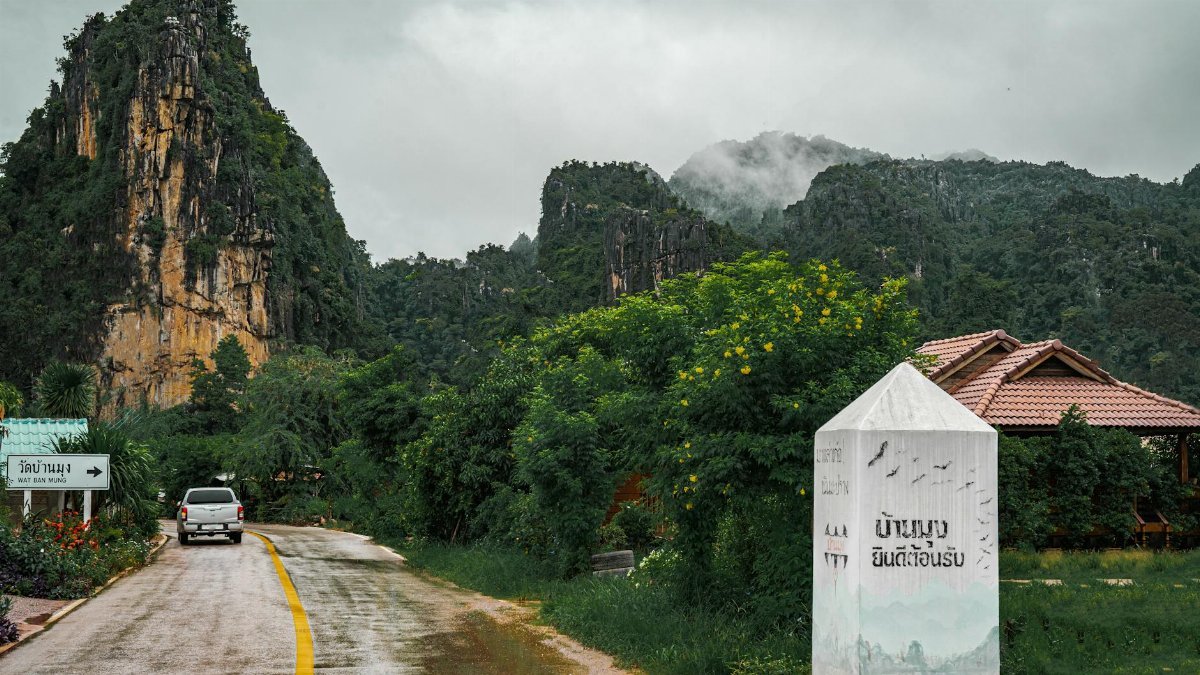 A picturesque road near Wat Ban Mung with misty mountains and lush greenery in rural Thailand.