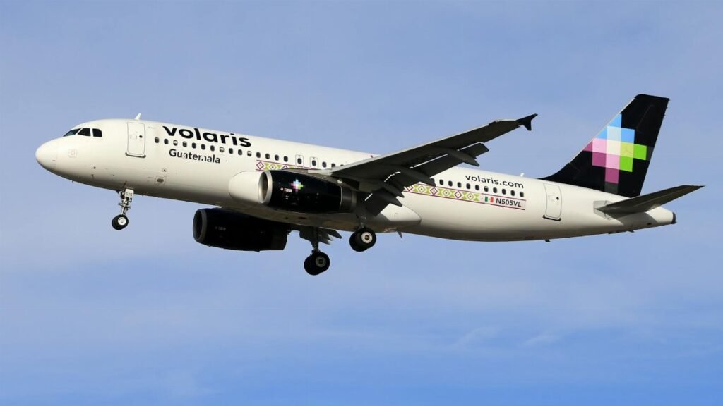 Volaris airplane in flight against clear blue sky, showcasing modern aviation.