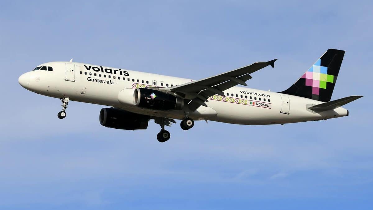 Volaris airplane in flight against clear blue sky, showcasing modern aviation.