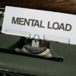 A vintage typewriter with a paper reading 'Mental Load', symbolizing stress and responsibility.