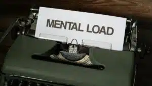 A vintage typewriter with a paper reading 'Mental Load', symbolizing stress and responsibility.