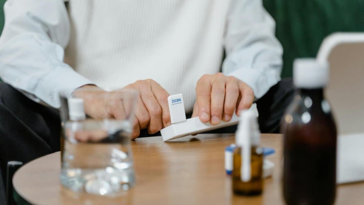 A senior adult preparing medicine doses at home, emphasizing healthcare and telehealth solutions.