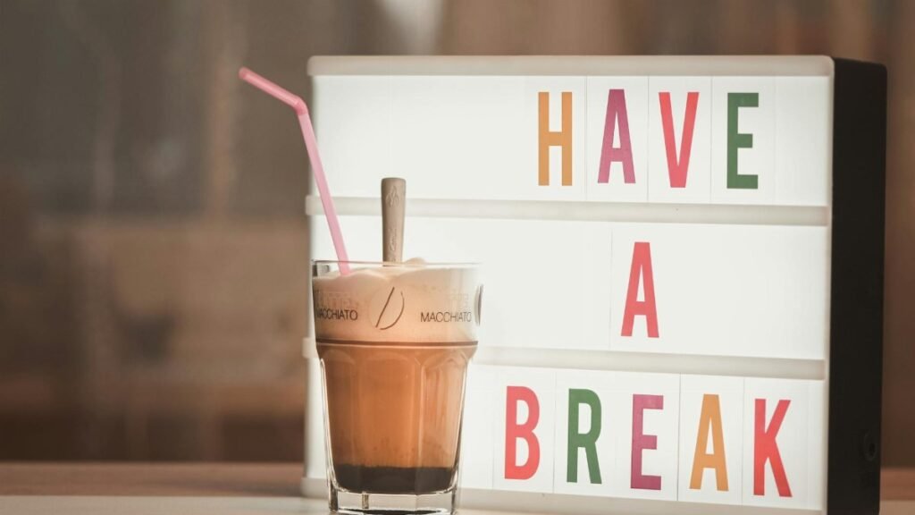 Iced coffee with straw beside illuminated light box saying 'Have a Break'.
