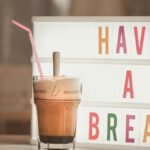 Iced coffee with straw beside illuminated light box saying 'Have a Break'.