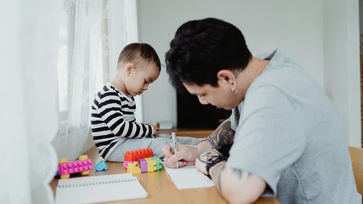 Father and son engaging in creative playtime with building blocks and drawing together.