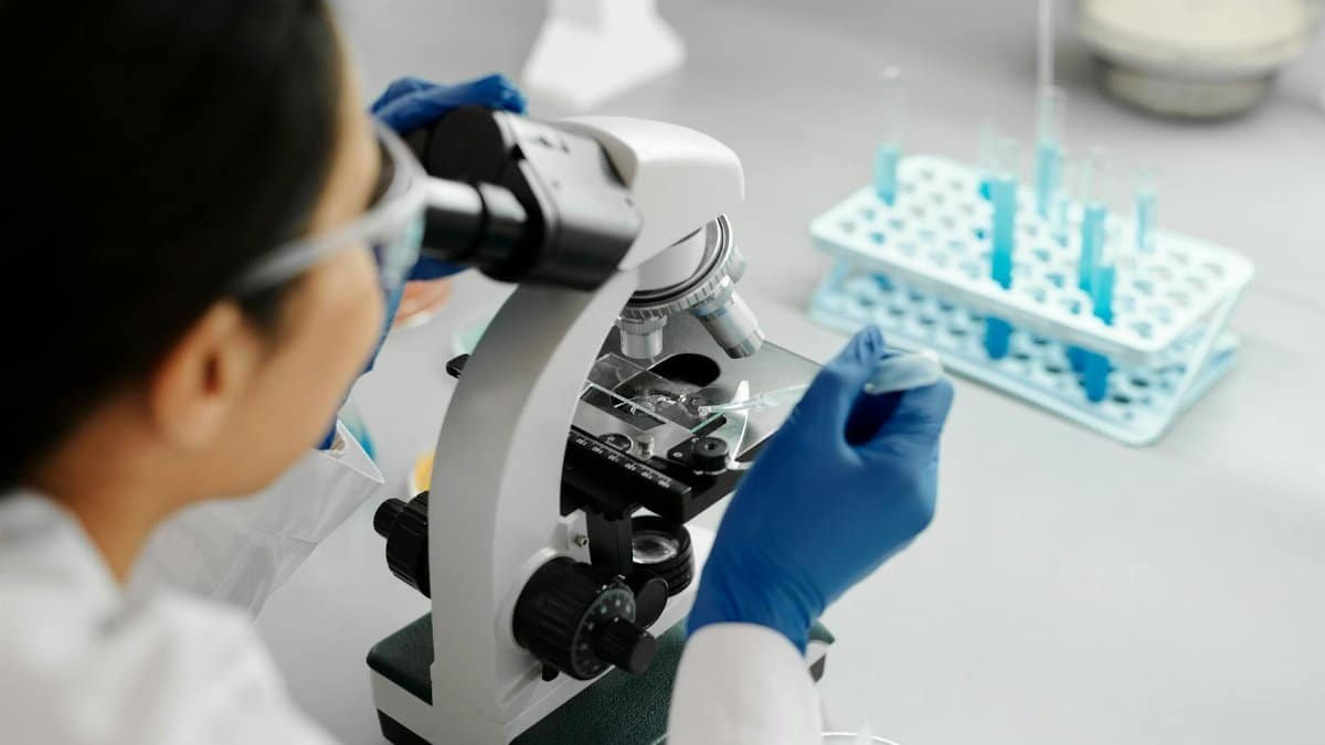 Scientist conducting research in a lab using a microscope and dropper.