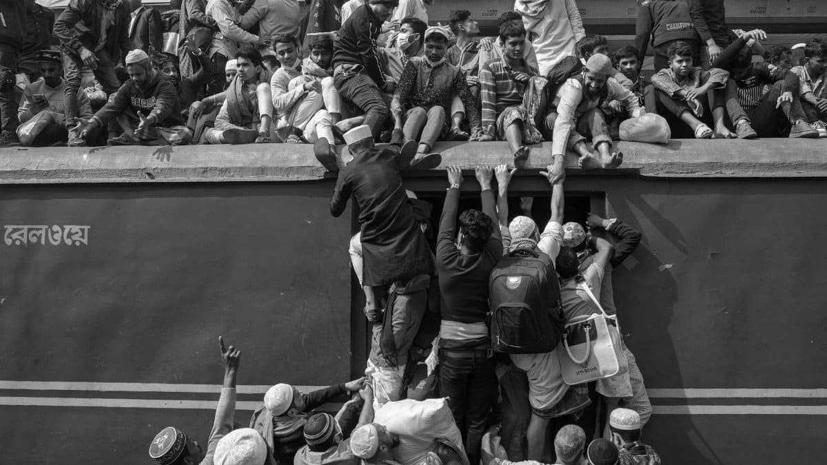Black and white photo of people crowded on and around a train, illustrating travel challenges.