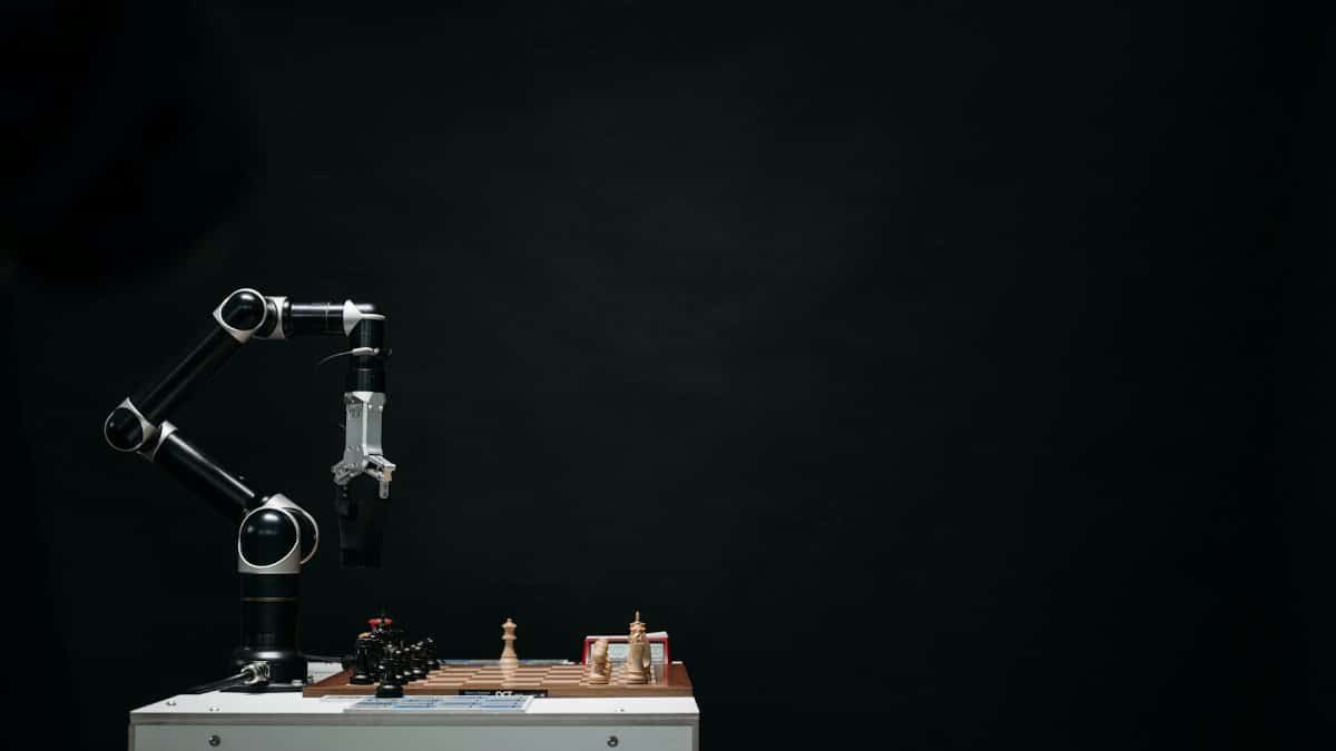 An articulated robotic arm competes in chess on a board against a dark background, highlighting AI and innovation.