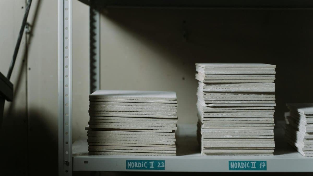 Stacks of ceramic tiles neatly arranged on industrial shelves in a dimly lit warehouse.