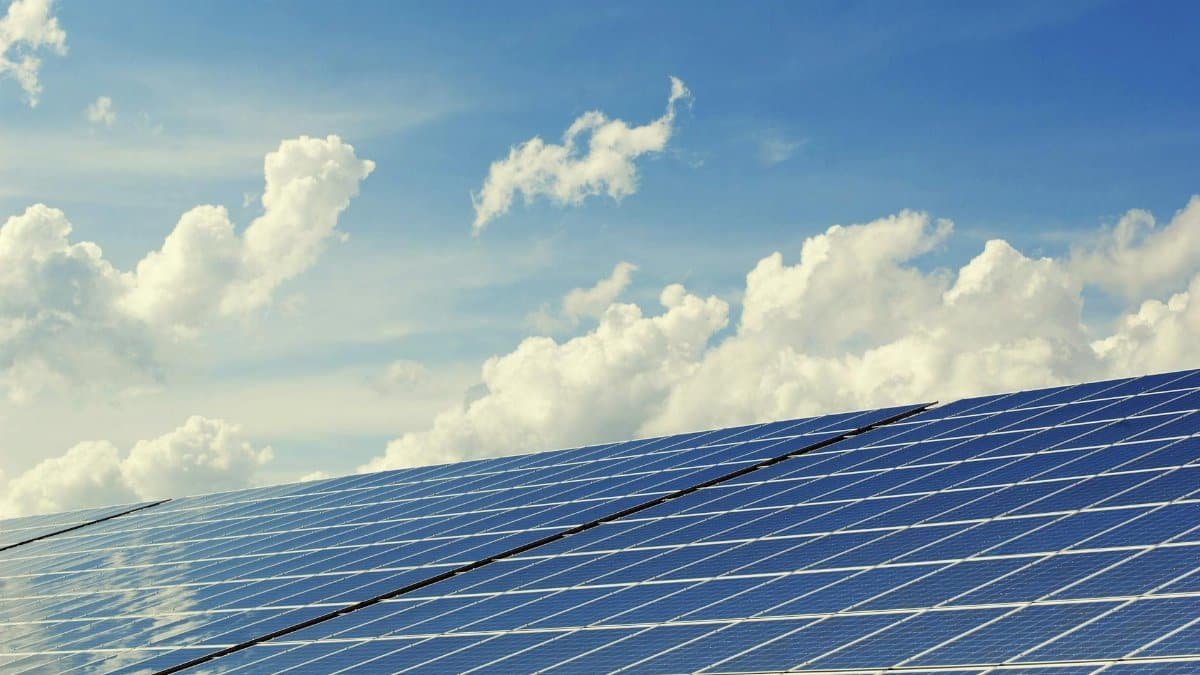 Sleek modern solar panels under a vibrant blue sky with clouds, symbolizing clean energy.