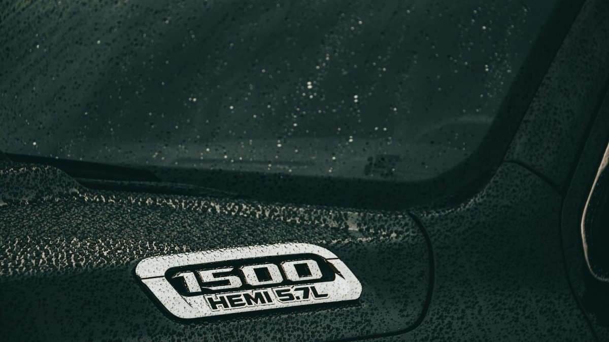 A close-up of a black Dodge Ram 1500 Hemi with rain droplets on the surface, showcasing automotive design.