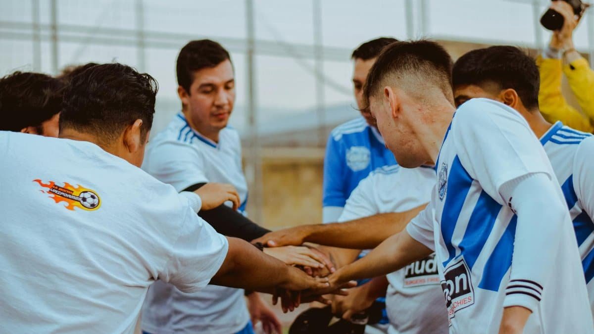 Young male soccer team in a huddle, showing unity and teamwork on the field.