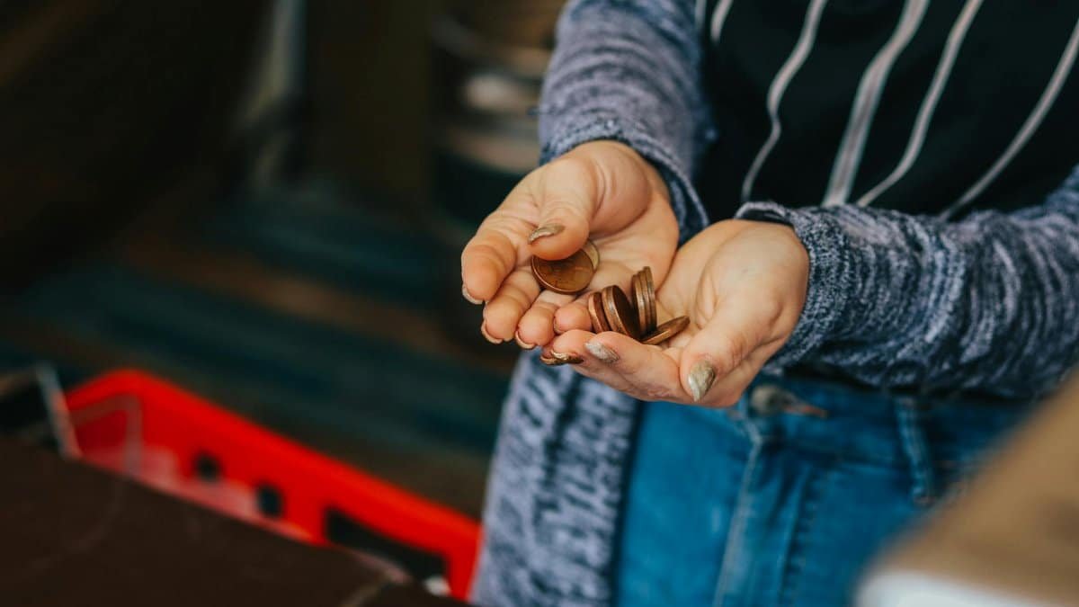 Close-up of a person's hands holding loose change at a Prague market.