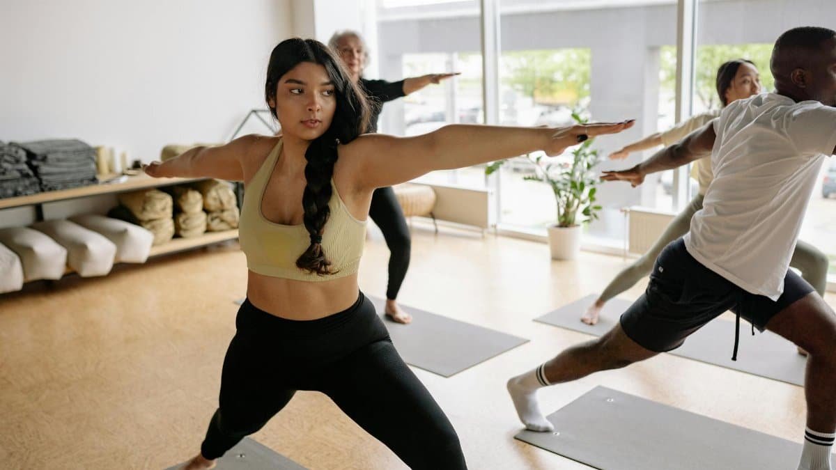 A diverse group of adults practicing yoga poses indoors.