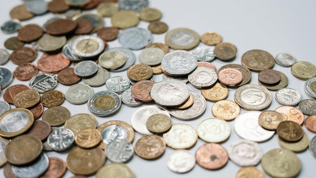 A diverse collection of international coins spread across a white surface, showcasing various currencies and designs.