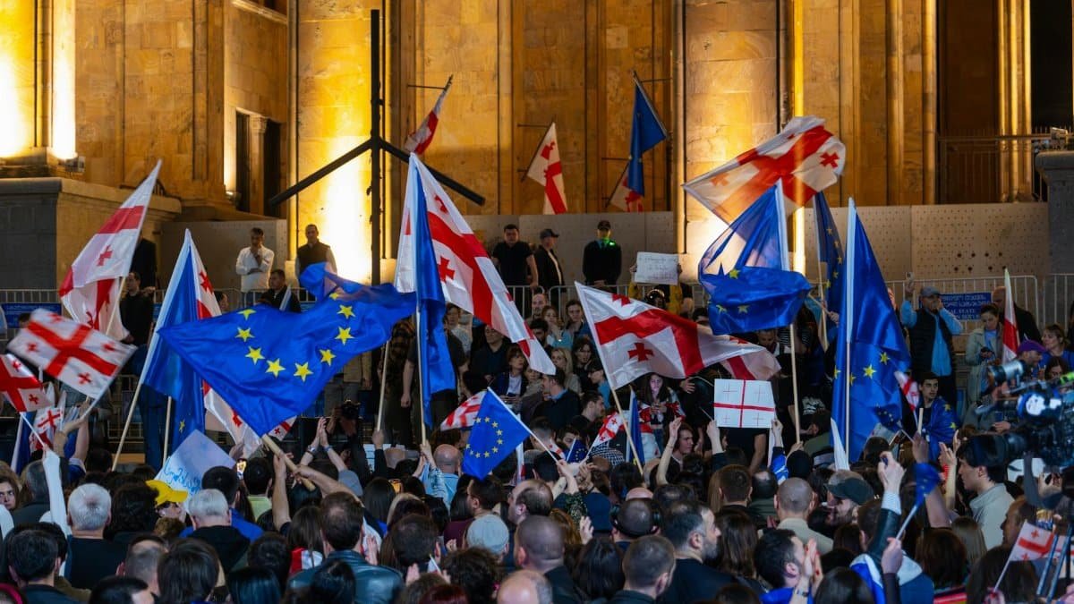 Crowd gathered in Tbilisi displaying Georgian and EU flags during a peaceful protest.